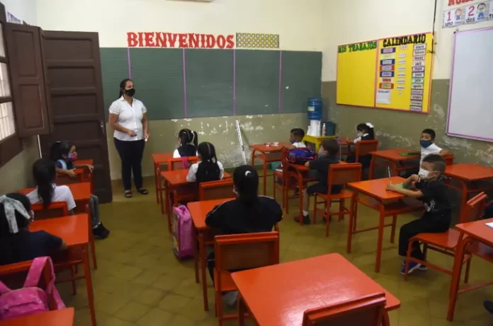 En clase. Docente conversa con sus estudiantes antes de iniciar las lecciones de la jornada en una escuela pública.